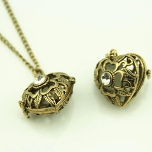 Detail of vintage hollow heart pendant necklace with floral carving and central faux diamond