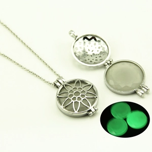 Détail du collier médaillon ajouré montrant la perle lumineuse verte dans le noir