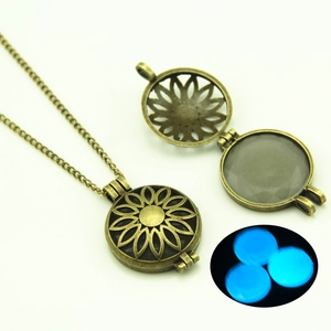 Detail of vintage hollow sunflower locket with glowing blue moonstone bead inside