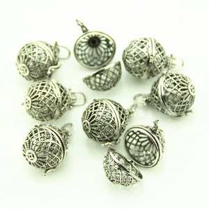 Detailed view of vintage silver hollow ball pendants with floral cutouts for DIY jewelry