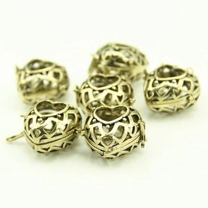 Detail of vintage bronze hollow heart-shaped pendants with intricate floral engraving
