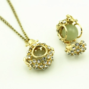 Macro shot of a hollow gold pendant with pavé crystals and a soft green stone