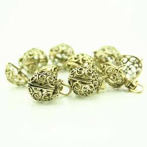 Close-up of vintage hollow heart metal pendants with floral engraving for DIY jewelry