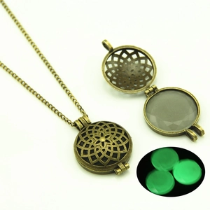 Detail of vintage hollow pendant with green luminous stone in dark light and open structure