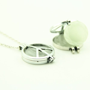 Collier médaillon signe de paix argenté ajouré avec pierre précieuse verte lumineuse