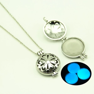 Pendentif médaillon argenté ajouré avec effet de lueur bleue lumineuse dans le noir