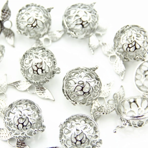 Detailed view of silver hollow carved aroma diffuser lockets and angel wing pendants