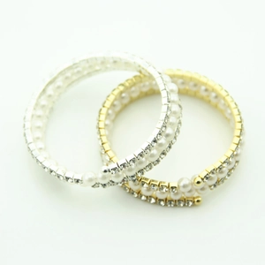Dettaglio di bracciali elastici a più file con perle e strass lucidi in oro e argento