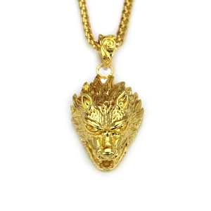 Macro detail of golden wolf head pendant featuring intricate carving and thick woven chain