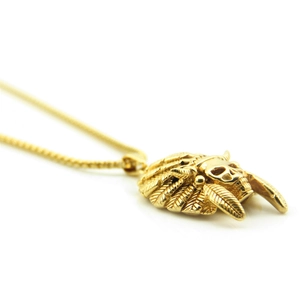Macro side view of gold punk Indian chief skull pendant with feather details