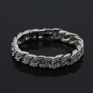 Detalle de una pulsera de eslabones cubanos plateada con pedrería sobre un fondo negro
