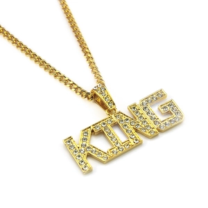 Macro shot of gold hip hop KING pendant with rhinestones and matching cuban link chain