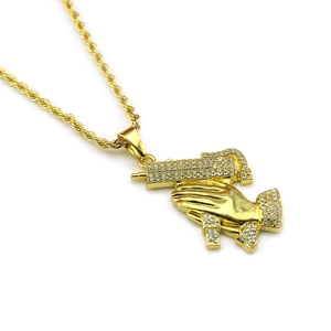 Vue macro détaillée du pendentif hip hop mains en prière et pistolet plaqué or brillant