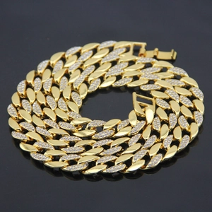 Men's 18K gold Cuban link necklace with iced out rhinestones on a dark reflective surface