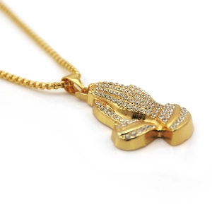 Vue macro du pendentif main en prière doré hip hop avec cristaux micro pavés brillants