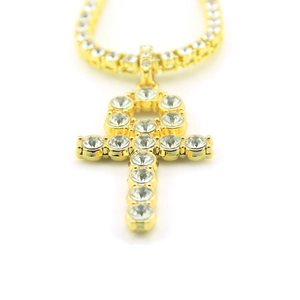 Macro view of iced out gold Ankh cross pendant with single row diamond tennis chain