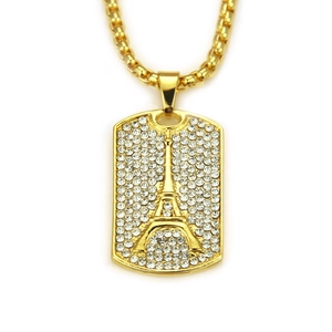 Detailed close-up of golden dog tag necklace with Eiffel Tower relief and inlaid crystals