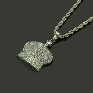 Macro detail of silver crown pendant with KING text and crystals on twisted rope chain