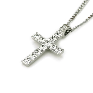 Gros plan détaillé d'un pendentif croix argenté avec des pierres de zircone cubique