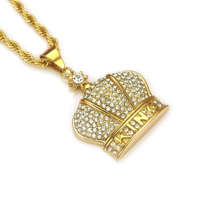 Close-up of golden crown pendant with iced out rhinestones and King letter engraving