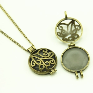 Detail of hollow openable round locket pendant with filigree vine patterns