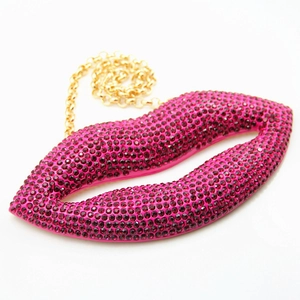 Macro detail of luxury red lip-shaped clutch with purple rhinestones and gold chain strap