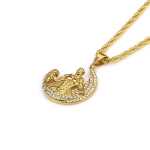 Détail du pendentif homme musclé doré sur une base en croissant de strass étincelante