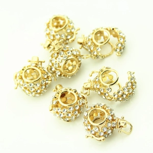 Macro detail of gold-plated hollow sphere pendants with pavé white rhinestones for DIY