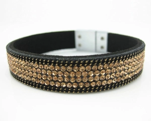 Macro view of black suede bracelet featuring triple rows of champagne gold rhinestones