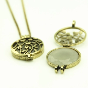 Vintage bronze hollow locket necklace with floral vine patterns and internal grey gemstone