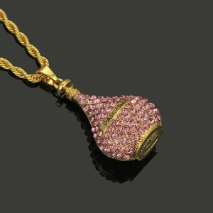 Détail du pendentif flacon de parfum doré orné de strass roses et gravure Parfum