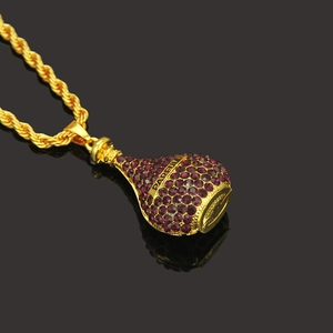 Détail macro du pendentif flacon de parfum doré avec strass violets et gravure PARFUM