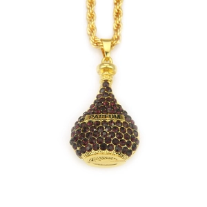 Vue détaillée du pendentif flacon de parfum doré avec cristaux violets et chaîne torsadée