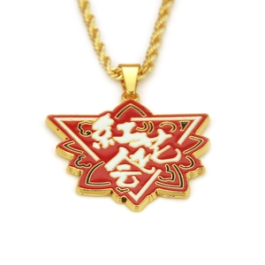 Détail macro du pendentif en émail rouge et blanc avec chaîne torsadée dorée hip-hop