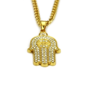 Close-up of golden Hamsa hand pendant with crystal pavé and evil eye detail on cuban chain