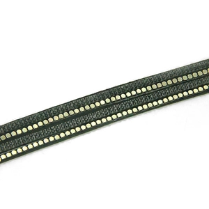 Vue macro du bracelet tressé noir avec trois rangées de clous hexagonaux dorés