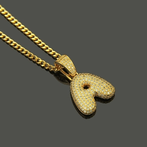 Macro shot of gold-tone Cuban chain and ice-out letter A pendant with micro zircons
