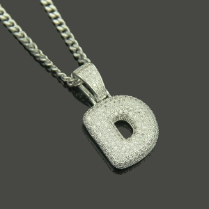 Macro view of iced out letter D pendant with cubic zirconia stones on Cuban link chain