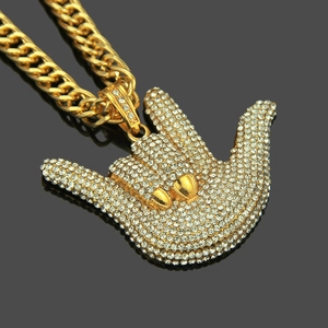 Vue macro du pendentif geste hip-hop en or avec cristaux pavés sur miroir noir
