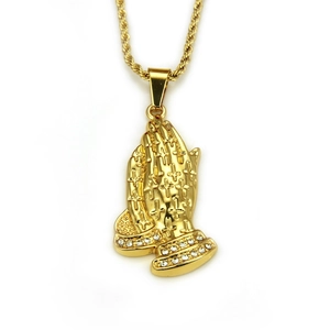 Detailed close-up of golden prayer hands pendant with cross patterns and rhinestones