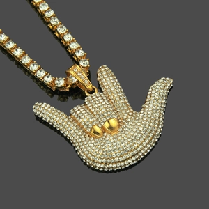 Macro detail of gold plated hip-hop hand gesture pendant with sparkling tennis chain