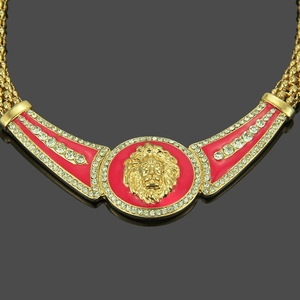 Close-up of golden lion head pendant with red enamel background and crystal rhinestones