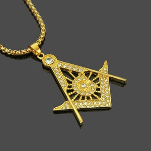 Vue macro du pendentif maçonnique doré avec lettre G et cristaux sur chaîne box