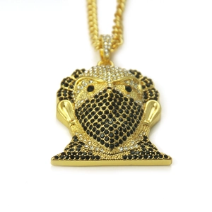 Détail macro du pendentif hip hop plaqué or avec strass noirs et blancs sertis