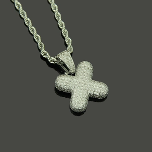 Macro shot of iced out letter X pendant with white zircons and metal rope chain