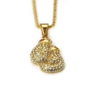 Macro shot of gold hip-hop boxing glove pendant with iced out rhinestones on a rope chain