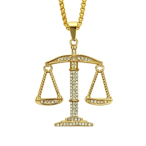 Détail macro du pendentif balance de justice doré avec incrustations de cristaux