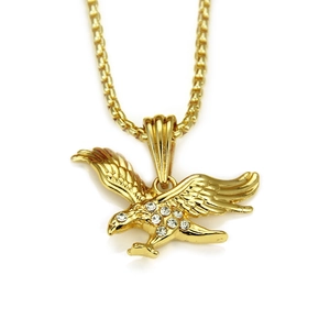 Macro detail of gold eagle pendant featuring spreading wings and inlaid white rhinestones