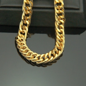 Bracelet gourmette épais plaqué or 18 carats avec reflets sur fond noir miroir