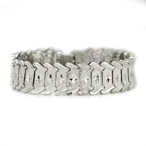 Macro shot of silver metal bracelet featuring textured links with embossed star motifs
